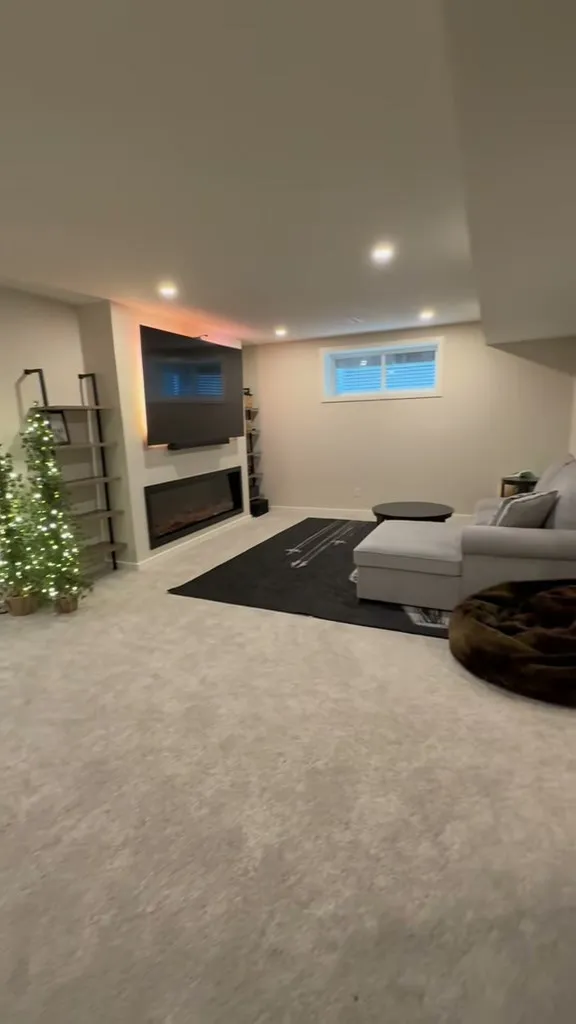 Finished Auburn Bay basement lounge with television, linear fireplace and sectional seating