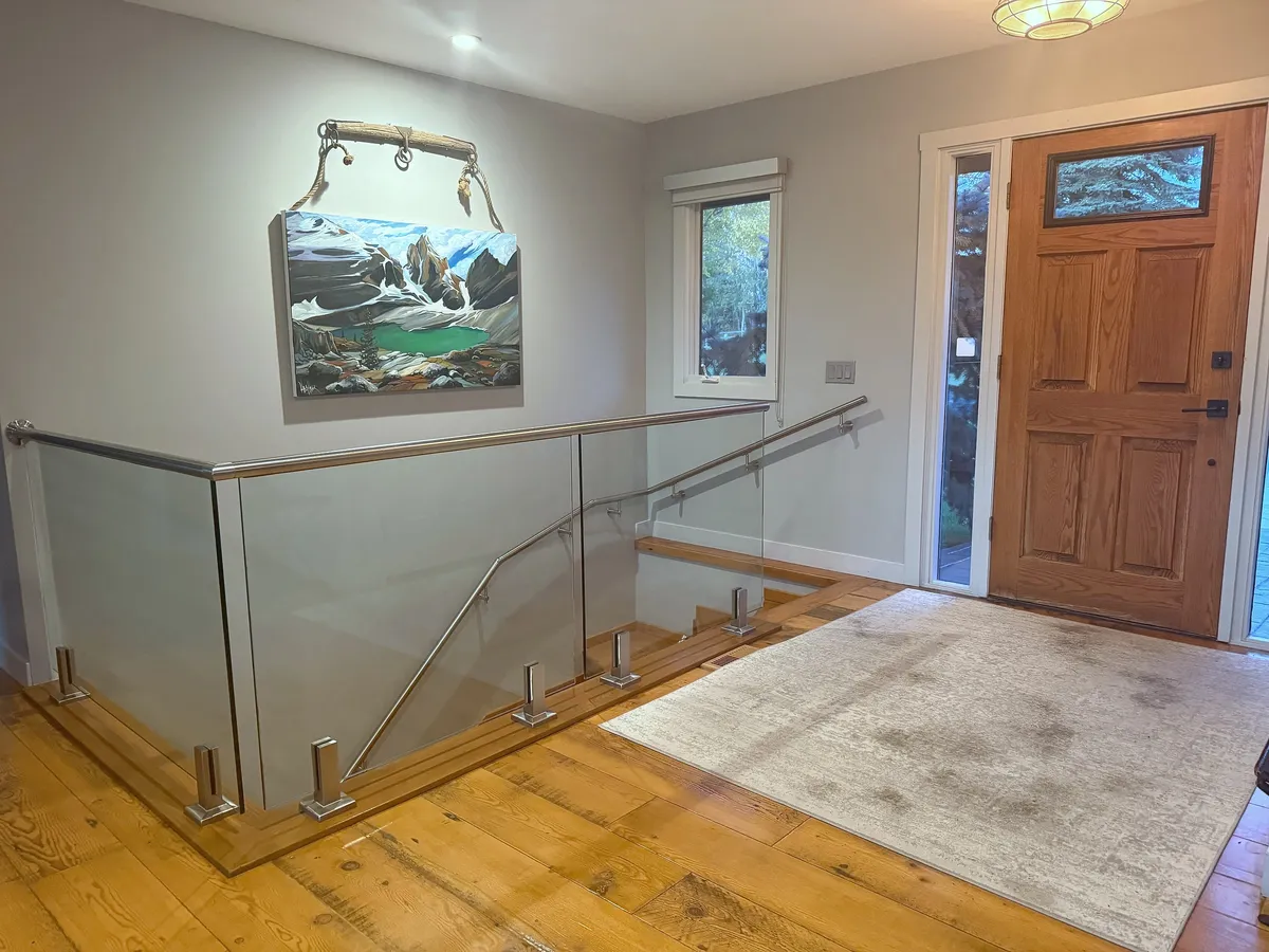 Glass stair railing and wood flooring in the renovated Artists View entry in Springbank