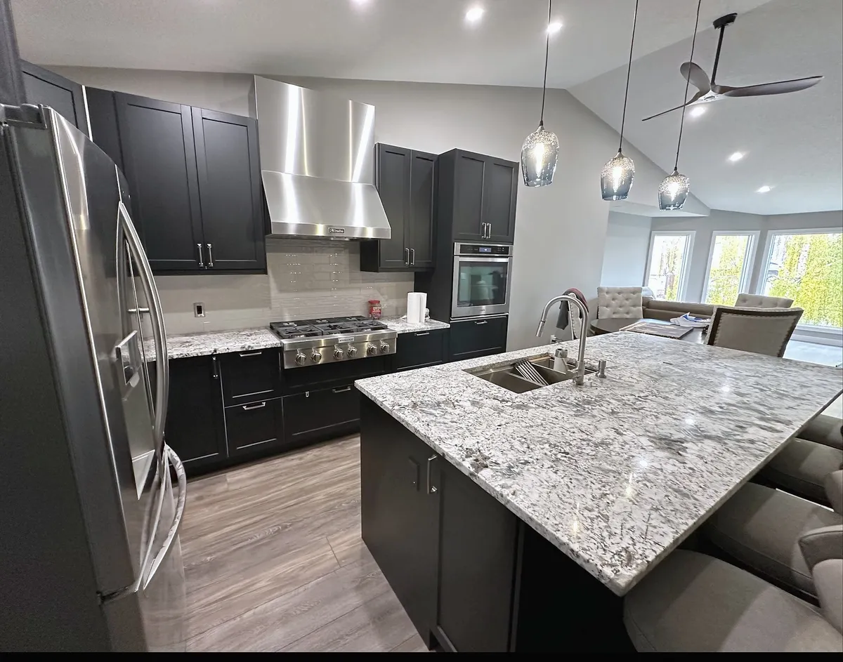 Harvest Hills kitchen with dark cabinets, patterned stone island and stainless range hood