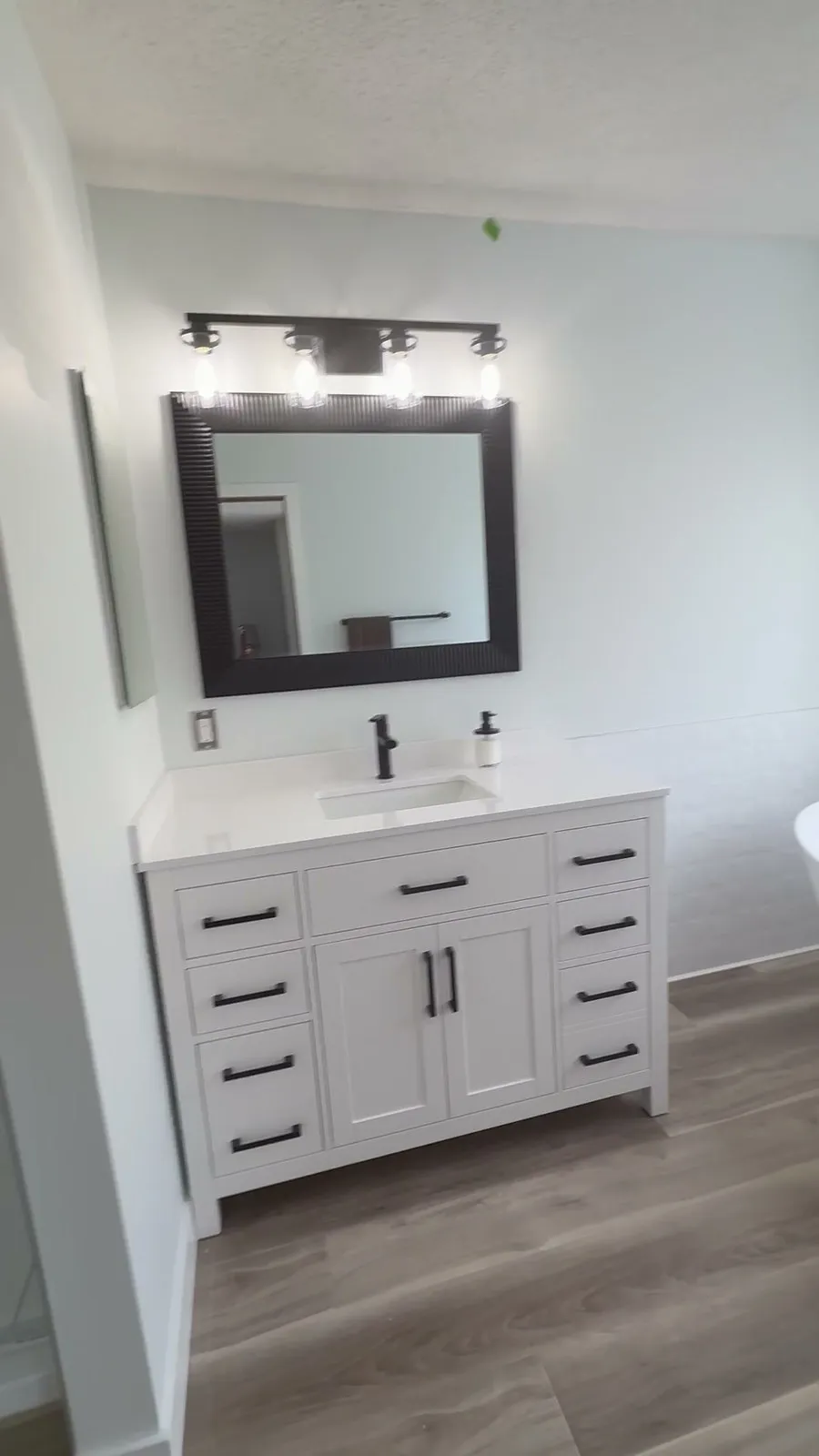 Aspen ensuite with a white vanity, black-framed mirror and coordinated black fixtures