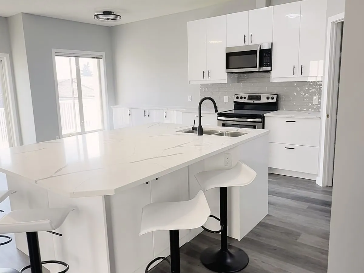White kitchen island with sink and curved bar stools in The Hamptons condo