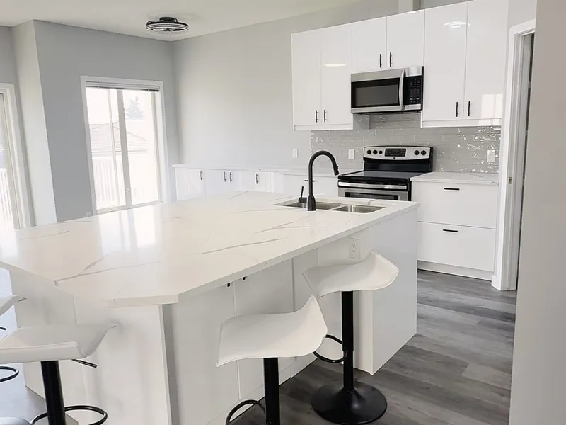 White kitchen island with sink and curved bar stools in The Hamptons condo