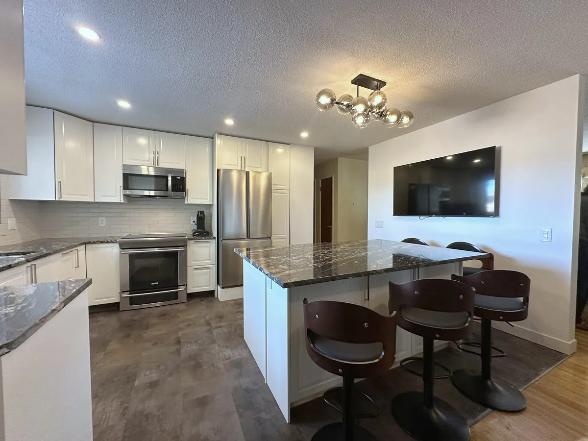 Dalhousie kitchen with a dark stone island, white cabinets and statement lighting