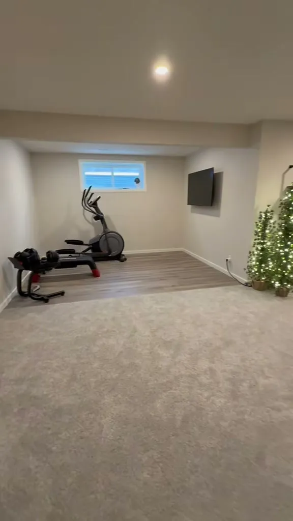 Auburn Bay home gym with exercise equipment beside the finished basement lounge
