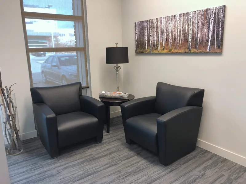 Client seating area with dark armchairs and artwork