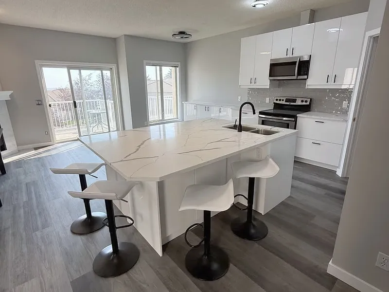 Open kitchen and dining area with white cabinetry and grey flooring