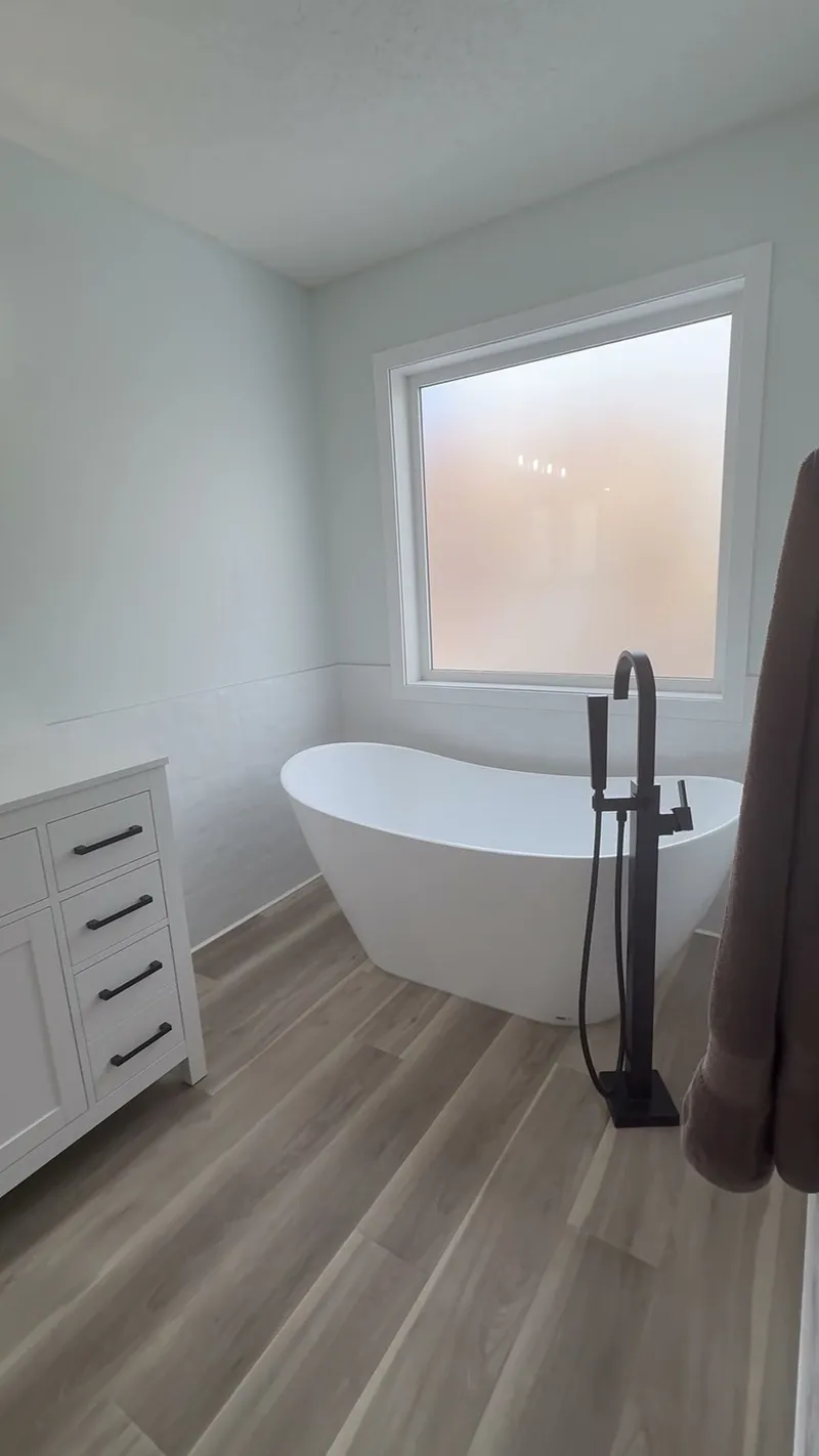 Freestanding bathtub beneath the Aspen ensuite window with black floor-mounted tap