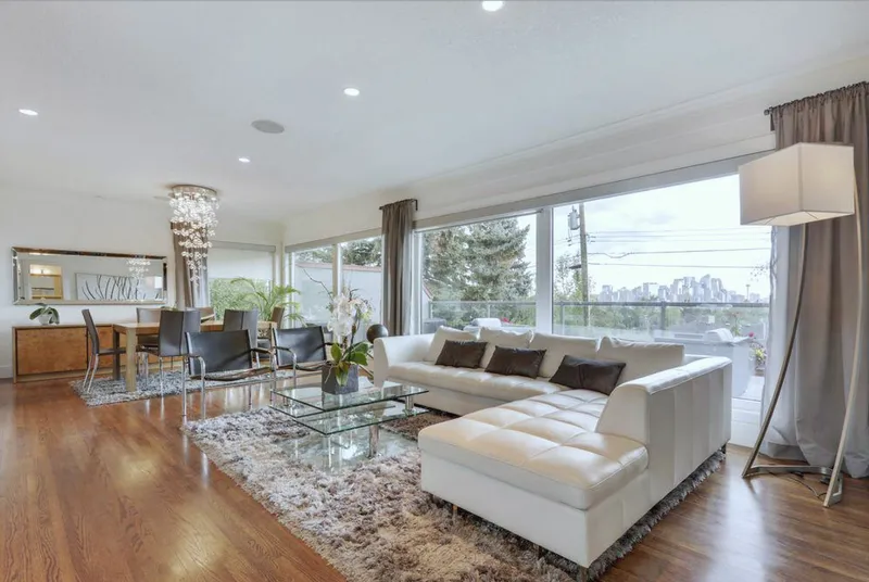 Open living and dining space with large windows and a white sectional