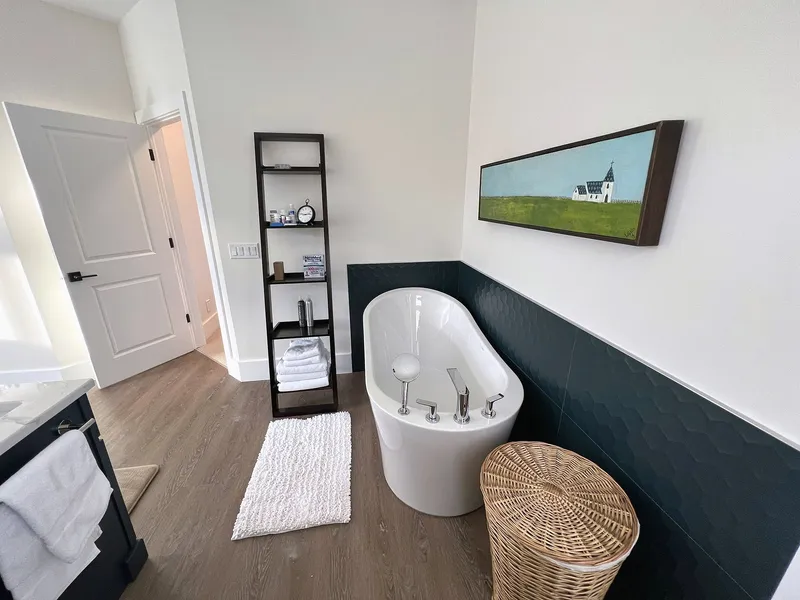 Freestanding tub against a dark accent wall in Bearspaw