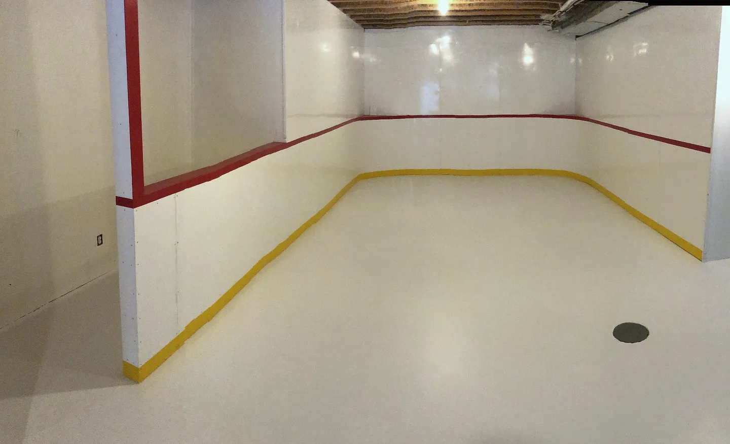 Completed indoor basement rink with white boards and red trim in Wentworth