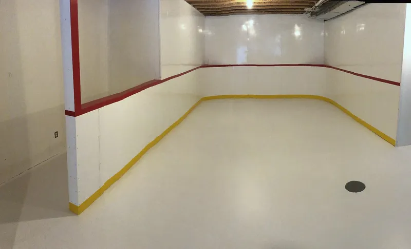 Completed indoor basement rink with white boards and red trim in Wentworth