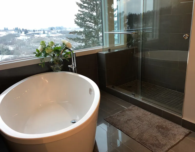 Freestanding bathtub and glass shower beside a large landscape-facing window
