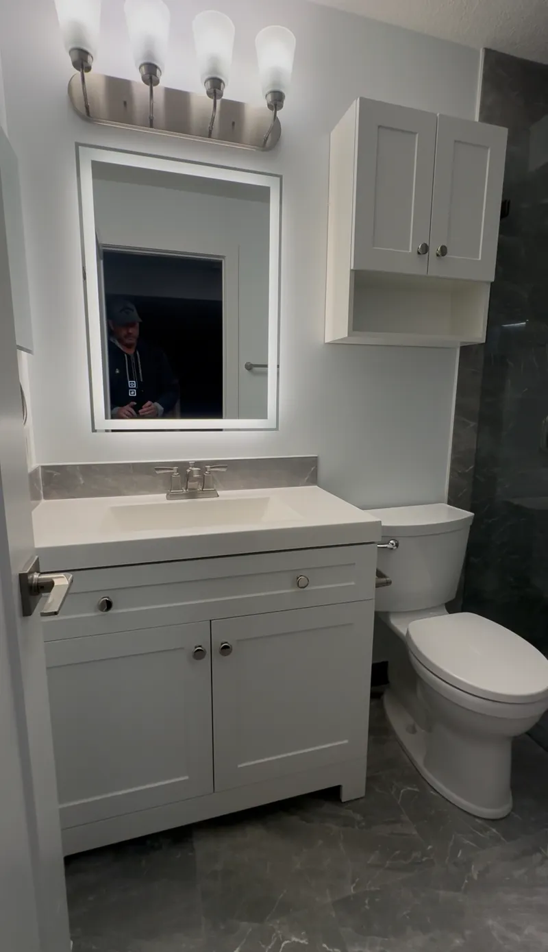 White bathroom vanity with mirrored cabinet and black tap