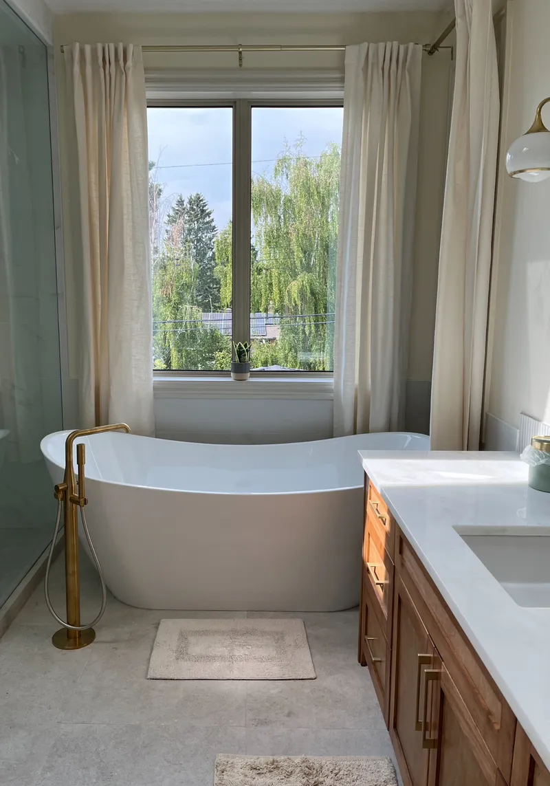 Bathroom with a freestanding tub, wood vanity and brass fixtures